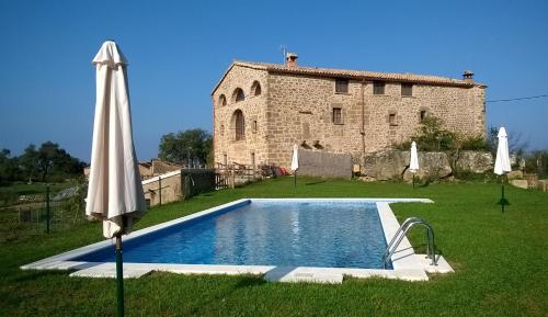 una piscina frente a un edificio con sombrilla en Masia Rovira, en Pinell de Solsonès