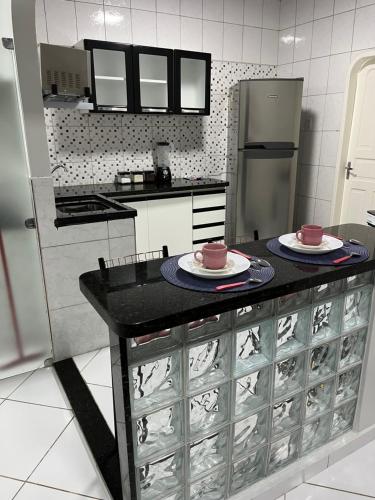 a kitchen with a counter with two plates and a refrigerator at Apartamento em Boa Vista in Boa Vista