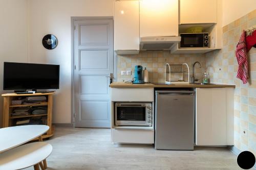 une cuisine avec un réfrigérateur et un micro-ondes dans l'établissement Appart Luchon au centre des allée d'etigny, à Luchon