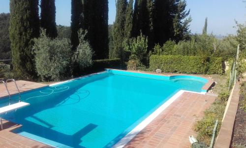 a blue swimming pool with trees in the background at Gervasella in Pontedera