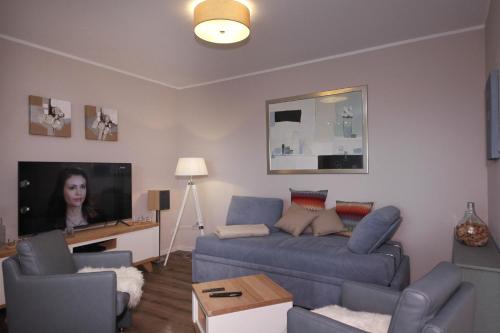 a living room with a blue couch and a tv at Ferienwohnung Kerst in Schweigen-Rechtenbach