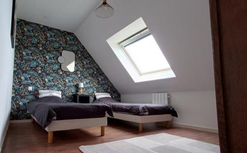 two beds in a attic bedroom with a window at Maison de vacances bord de mer Sibiril Moguériec finistère la villa Léonie in Sibiril