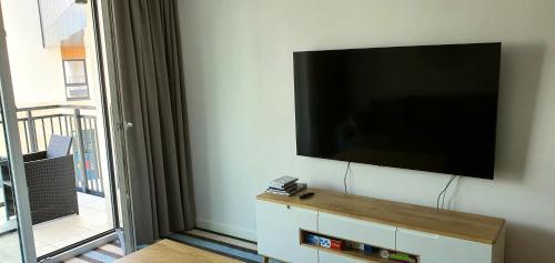 TV de pantalla plana colgada en la pared en Apartament Bel Mare, en Międzyzdroje
