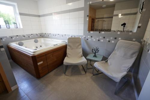uma casa de banho com banheira e 2 cadeiras em Apartmány Sunny hill em Frymburk