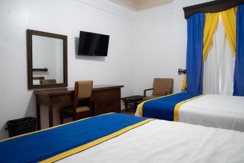 a hotel room with two beds and a desk and a mirror at Hotel Sierra Gorda in Ciudad Victoria