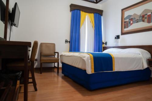 a bedroom with a bed with blue and yellow curtains at Hotel Sierra Gorda in Ciudad Victoria