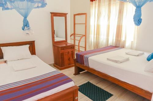 a bedroom with two beds and a mirror at Lakeside Villa in Anuradhapura