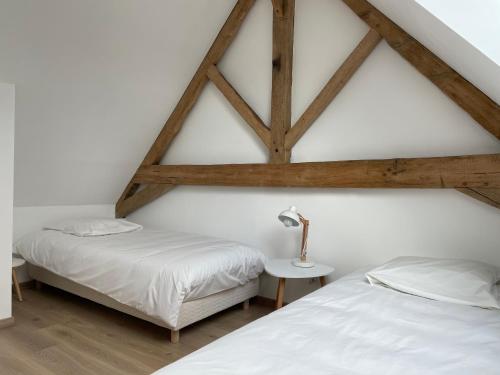 two beds in a room with wooden ceilings at GÎTE 2 Ferme de la Haute Escalles in Escalles