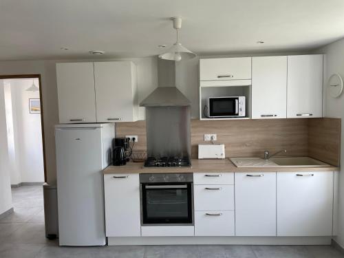 une cuisine avec des armoires blanches et un four à plaques de cuisson dans l'établissement GÎTE 2 Ferme de la Haute Escalles, à Escalles