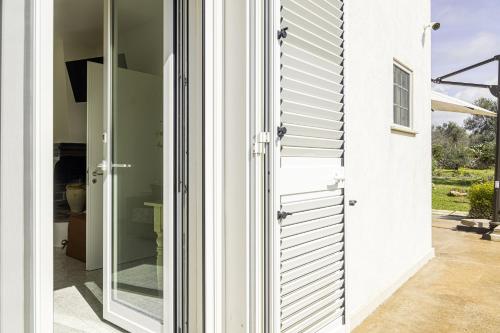 a pivot door in a white house with a glass doorway at SalentOspita Guest Rooms in Torre San Giovanni Ugento