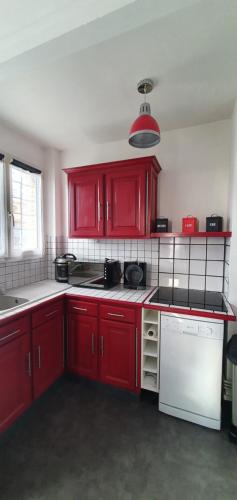 - une cuisine avec des placards rouges et un lave-vaisselle blanc dans l'établissement Le Tréport vue sur mer et sur l entrée du port, au Tréport