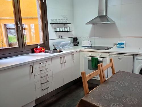 a kitchen with white cabinets and a sink and a table at Apartamento CASCO HISTÓRICO in Allariz