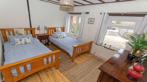 1 dormitorio con 2 camas, mesa y ventana en Shippenrill Croyde - Sleeps 14 - Hot Tub option - Stylish Home with fire pit, table tennis & dog friendly, en Croyde