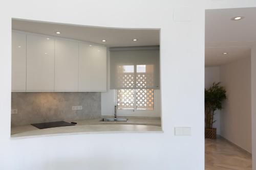 een keuken met witte kasten en een wastafel bij Apartamentos Las Americas in Islantilla