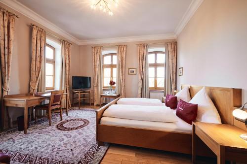 um quarto com uma cama, uma secretária e uma televisão em Hotel & Restaurant Waldschloss em Passau