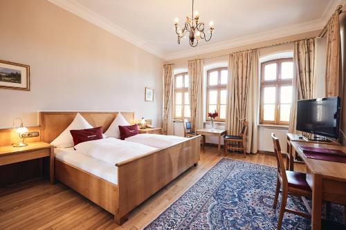 a bedroom with a bed and a desk and a television at Hotel & Restaurant Waldschloss in Passau