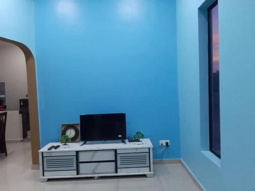 a living room with a tv on a blue wall at Homestay Armand Pengkalan Balak Melaka in Masjid Tanah