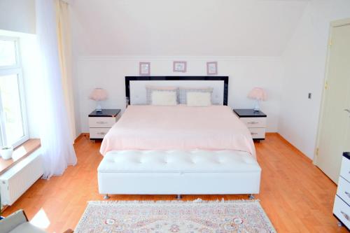 ein weißes Schlafzimmer mit einem weißen Bett und zwei Nachttischen in der Unterkunft Garden Cottage near Beach, Airport in Baku
