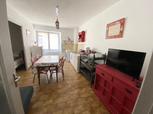 eine Küche mit einem roten Schrank und einem Tisch mit einem TV in der Unterkunft Studio en rez-de-chaussée tout équipé in Jullianges