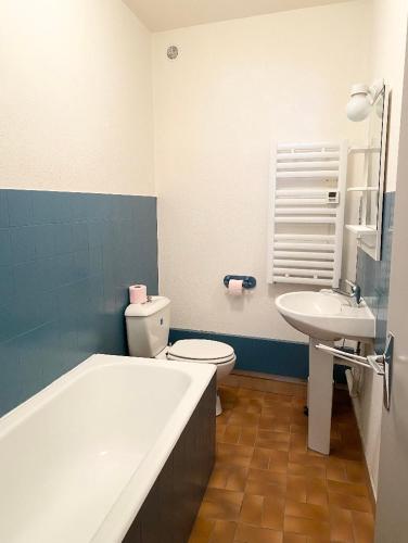 ein Badezimmer mit einer Badewanne, einem WC und einem Waschbecken in der Unterkunft Studio en rez-de-chaussée tout équipé in Jullianges