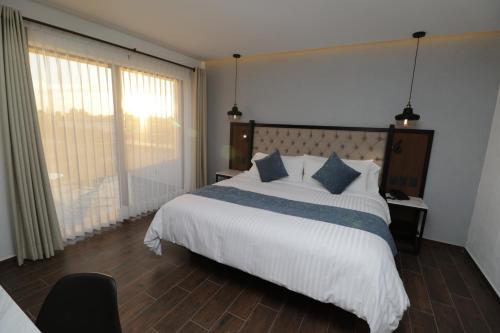 a bedroom with a large white bed with blue pillows at Hotel Boutique Casa Loreta in Querétaro