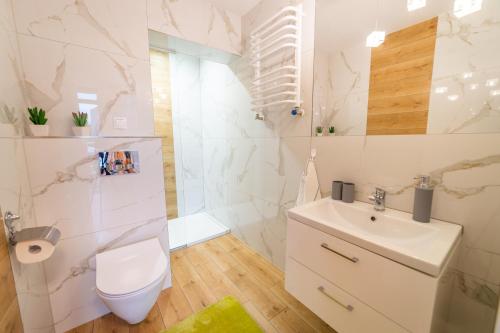 a white bathroom with a toilet and a sink at Pokoje u Matiego in Mikołajki