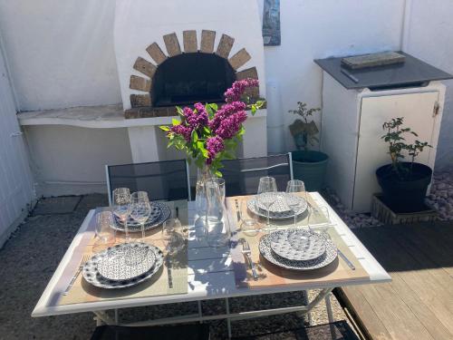 une table avec des assiettes et un vase avec des fleurs. dans l'établissement Studio avec grande terrasse et jardin privatif au Pyla, à La Teste-de-Buch