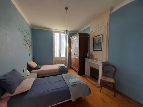 Cette chambre bleue comprend 2 lits et une cheminée. dans l'établissement Domaine du Grand Ormeau, à Semillac