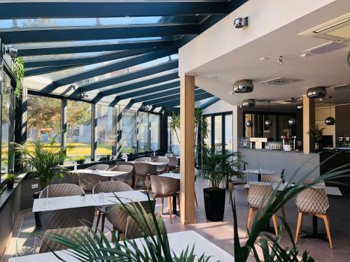 a restaurant with blue ceilings and tables and chairs at Hét Vezér Apartmanhotel in Komárom