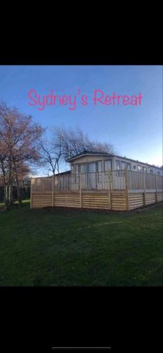 a wooden fence in a yard with a building at Caravan on Fantastic site in Dunbar
