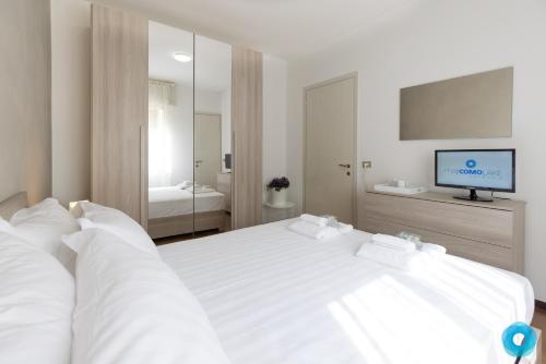 a bedroom with a white bed with a tv on the wall at Maji Como Lake Varenna in Varenna