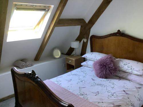 a bedroom with a bed with a purple pillow on it at Le Petite Barn in Vautorte