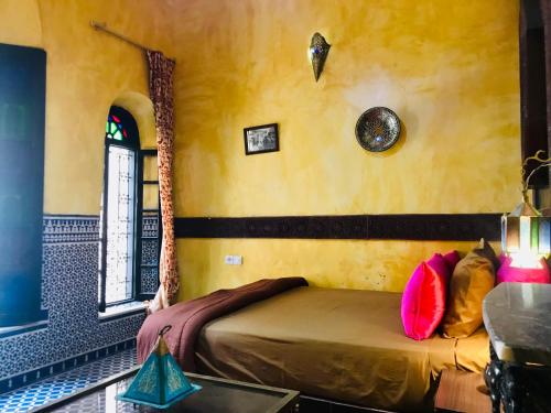 Riad Safari Fes في فاس: غرفة نوم مع سرير مع وسائد ملونة