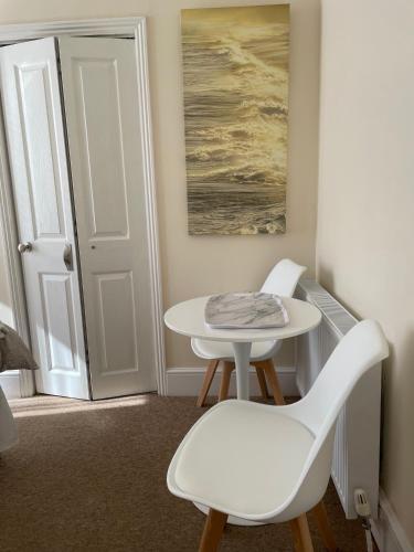 a white table and chairs in a room with a door at CARIS Guest House in Southend-on-Sea