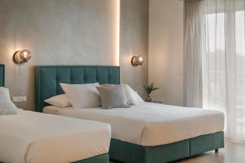 two beds in a bedroom with a green headboard at Socrates Apartments in Skala Kefalonias