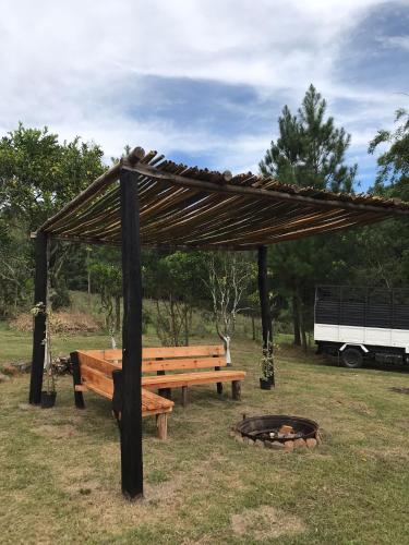 a wooden bench and a fire pit with a canopy at Cabaña Los Nietitos in Tranqueras
