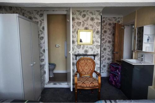 Un baño con una silla, un lavabo y un inodoro. en Dunromin Hotel, en Blackpool