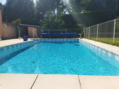 een groot zwembad met blauw water in een tuin bij Chambres Tricastine & Venise in Saint-Paul-Trois-Châteaux