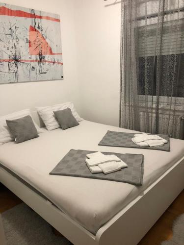 un letto bianco con sopra asciugamani di S-Lux apartman a Sombor