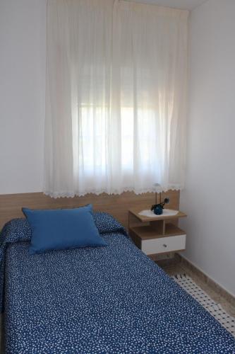 a bedroom with a blue bed and a window at Apartamentos Os Cerros in Portonovo