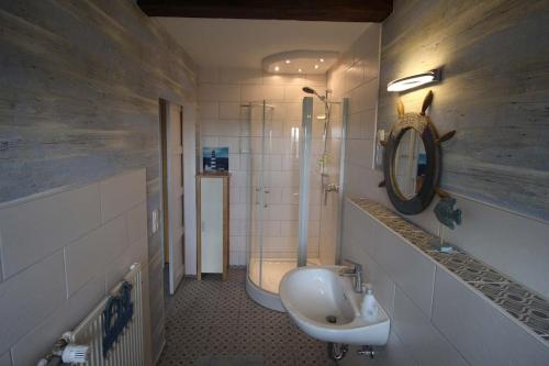 a bathroom with a sink and a toilet and a mirror at Ferienhaus auf einer Warft in Tetenbüll