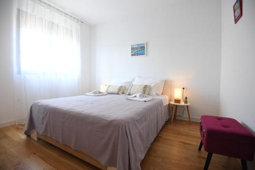 a white bedroom with a large bed with a window at Apartment Maritimo in Zadar