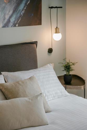 a bed with white sheets and a table with a potted plant at Socrates Apartments in Skala Kefalonias