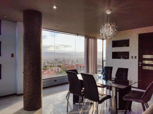 uma sala de jantar com mesa e cadeiras e uma grande janela em Las vistas - Departamento independiente em Cochabamba