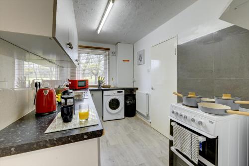 a kitchen with a stove and a washer and dryer at 3-bed House, sleeps 8, Next to Park in Northampton