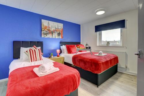 ノーサンプトンにある3-bed House, sleeps 8, Next to Parkのベッドルーム1室(赤いシーツと青い壁のベッド2台付)