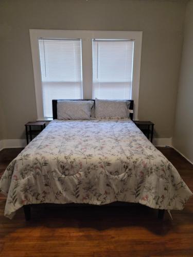 a bedroom with a bed with a floral bedspread and two windows at Luxurious 3 bedroom near downtown in San Antonio