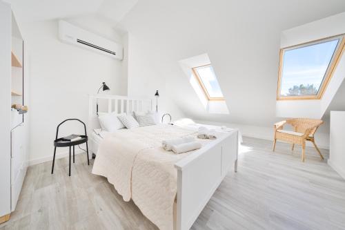 a white bedroom with a white bed and a chair at Apartament Lubię Morze in Jantar