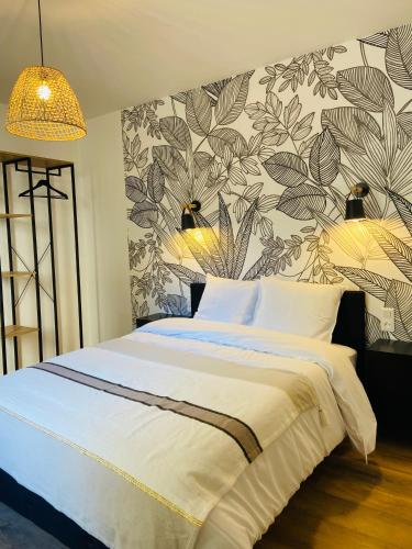1 dormitorio con 1 cama grande y papel pintado con motivos florales en Appartement 2 chambres avec terrasse vue sur jardin arboré en Pontarlier