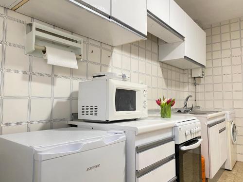 a white kitchen with a microwave and a dishwasher at Apartamento Padrón Centro P3 by URent in Padrón